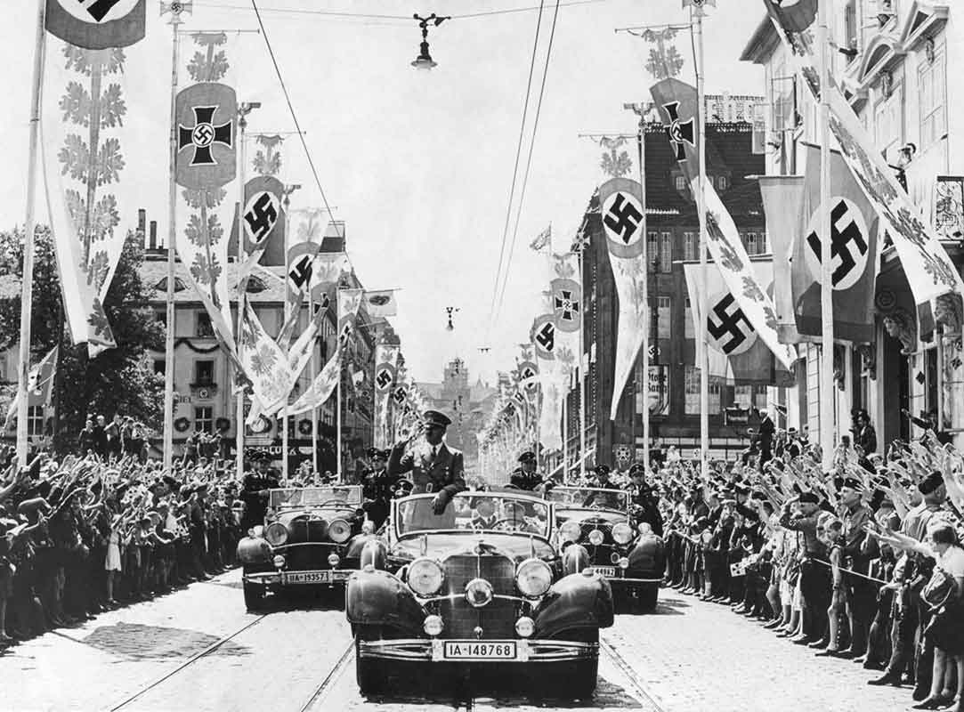 Adolf Hitler saluta la folla dalla sua auto alla testa di un corteo